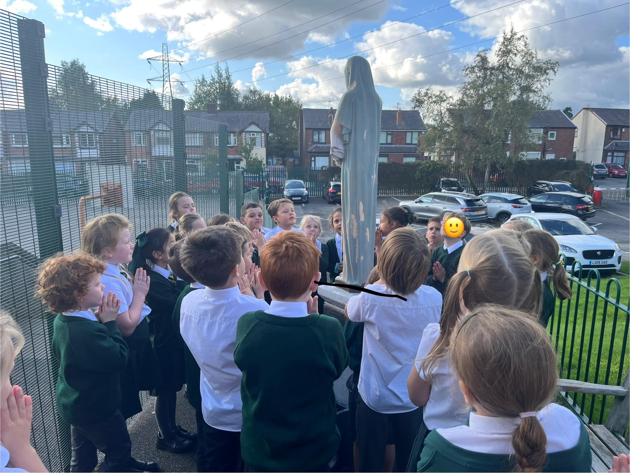 Year three gather around Our Lady's Statue to  pray the Rosary.
